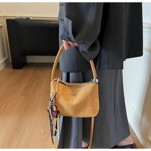 Detailed view of yellow faux suede bucket bag with decorative scarf and bear charm
