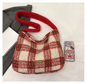 Detailed close-up of a plaid wool tote bag with a stitched brown leather logo patch