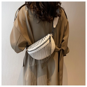 Detail view of white half-moon crossbody bag with silver rivets and metal tassels