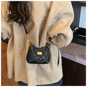 Detail of a black quilted leather crossbody bag with gold chain and metal twist lock