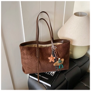 Macro detail of dark brown woven tote bag with smooth texture and stylish star pendant