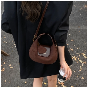 Detail of dark brown hobo bag with heart pendant and suede leather stitching detail