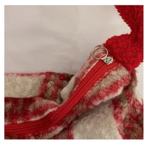 Detail of red smooth zipper and silver round metal ring on plaid wool tote bag