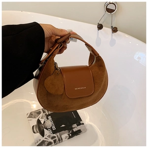 Detail of a brown crescent bag in suede and leather with heart charm and brand logo