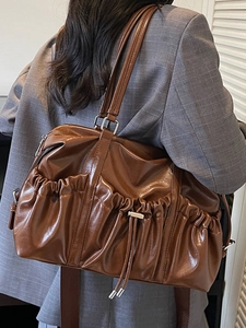 Large dark brown vintage pleated tote bag with drawstring detail worn on shoulder