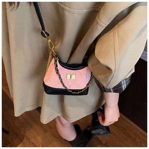 Detail of pink quilted suede crossbody bag with black leather trim and gold turn-lock