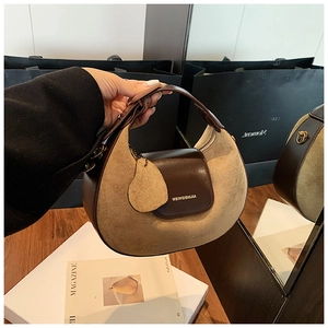 Detail shot of the two-tone brown leather crescent bag with suede panels and a pear-shaped tag