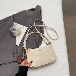 Detail of minimalist beige bucket bag with creative leopard bear charm on gray blazer