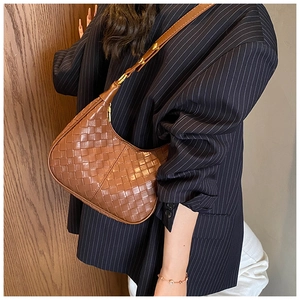 Close-up of brown woven crescent bag showing detailed leather texture and gold buckle