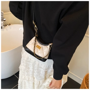 Close-up of contrast trim on a cream quilted crossbody bag with metal chain strap
