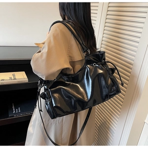 Detail view of glossy black faux leather tote bag with drawstring and silver hardware