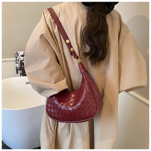 Close-up of a burgundy woven leather crescent bag with elegant gold hardware and strap