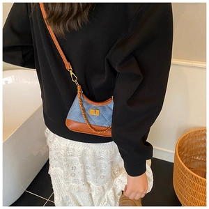 Model wearing a blue quilted denim mini crossbody bag with brown leather trim details