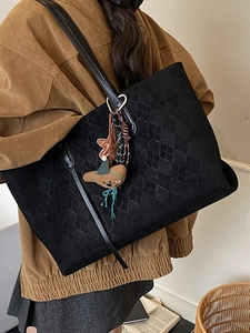 Large black quilted tote bag with bear charm shown on model for autumn commute