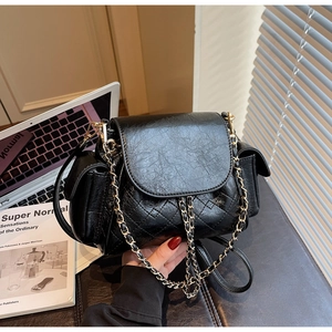 Macro detail of black quilted leather crossbody bag with golden chain and accordion gusset