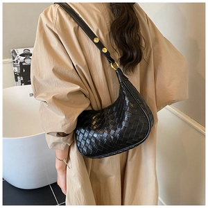 Macro detail of the black woven leather crescent bag with a gold metal buckle