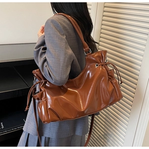 Detail of caramel brown glossy patent leather tote bag with drawstring texture
