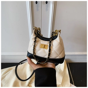 Detail of contrast-colored quilted mini bag with golden twist lock and chain strap