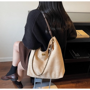 Détail du sac hobo beige avec bandoulière en cuir marron et breloque en perles