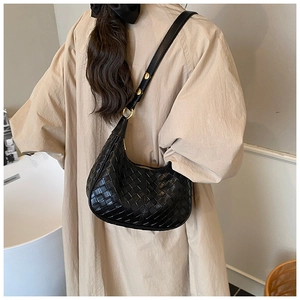 Detailed view of black woven leather hobo bag with gold buckle on a model in a trench coat
