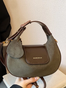 Retro crescent-shaped handbag in army green suede with brown leather trim held by hand