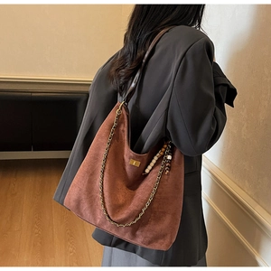 Détail du grand sac cabas en suédine avec bandoulière chaîne et pompon perlé à l'épaule