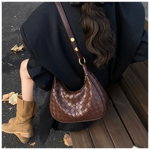 Detailed close-up of dark brown woven leather texture on a crescent shoulder bag