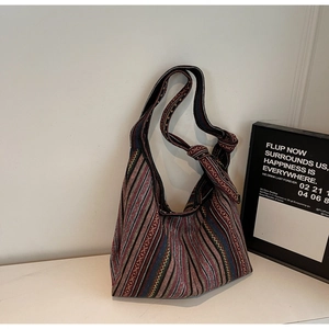 Detailed view of bohemian striped woven canvas tote bag with rustic texture and knotted strap