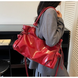 Detail of red oversized leather tote with drawstring accents and pleated design