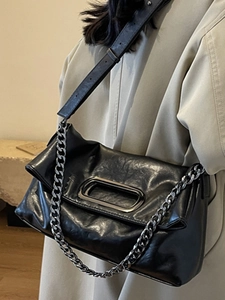 French retro black leather chain pillow bag shown on a model with an adjustable strap