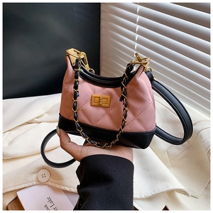 Detail of pink and black suede crossbody bag with gold rotating lock and metal chain