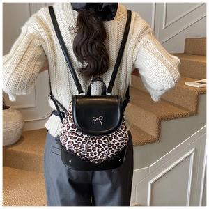 Détail d'un mini sac à dos imprimé léopard avec nœud doré sur une tenue décontractée