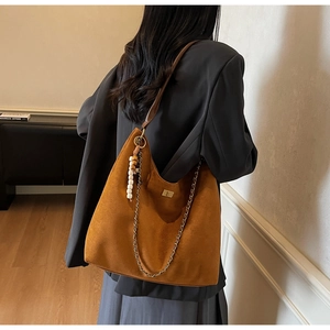 Détail d'un grand sac hobo en daim marron avec pendentif en perles de bois et chaîne