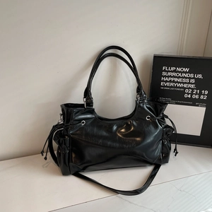 Detailed close-up of a black glossy PU leather shoulder bag with side drawstring and metal eyelets