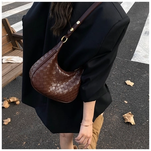 Detail of dark brown woven hobo bag showing luxury texture and golden hardware