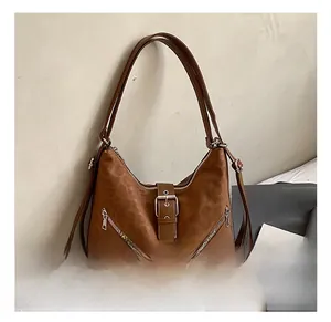 Detail of brown hobo bag showing embossed texture and diagonal zipper accents