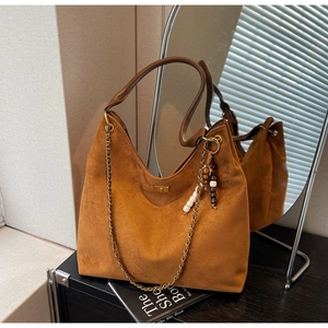 Gros plan d'un sac cabas en daim marron avec bandoulière en cuir et charm perlé élégant