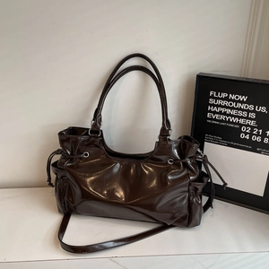 Macro detail of dark brown glossy patent leather shoulder bag with side drawstring pleats