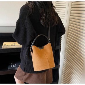 Detailed view of the brown suede bucket bag featuring adjustable leather strap and logo