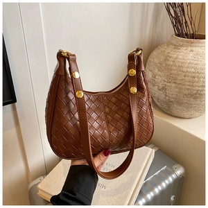 Detail showing the intricate woven texture and large gold buckle of the crescent bag