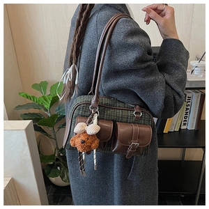 Detail of vintage plaid Boston bag with leather pockets and cute teddy bear charm