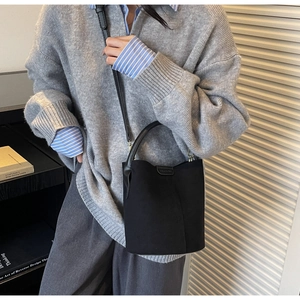 Detail of minimalist black matte bucket bag styled with a professional casual outfit