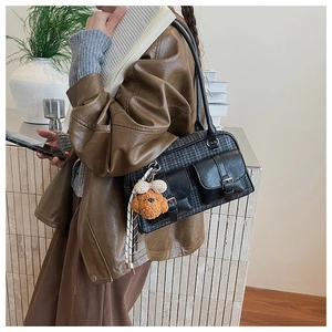 Detail of vintage plaid shoulder bag with leather straps and a cute plush dog pendant