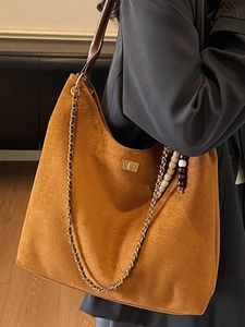 Sac hobo en daim marron avec bandoulière chaîne et pompon boho pour un look élégant