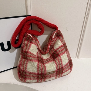 Detail showing the red and white checkered plush texture and brown leather label on bag