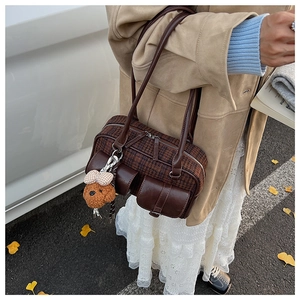 Detail of vintage plaid Boston bag with decorative pockets and cute bear plush pendant