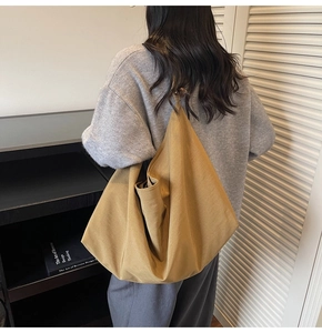 Detail einer ingwergelben Canvas Hobo-Tasche, die von einem Model über der Schulter getragen wird