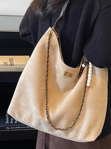 Grand sac cabas minimaliste en daim beige avec chaîne dorée porté par un mannequin