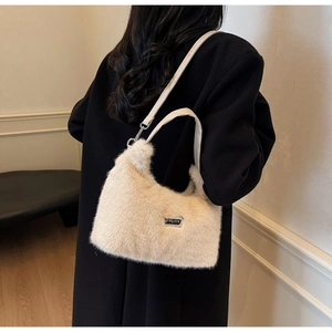 Rear view of a plush cream faux fur shoulder bag worn over a stylish black winter coat