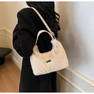 Detail of plush beige shoulder bag with adjustable leather strap on black coat
